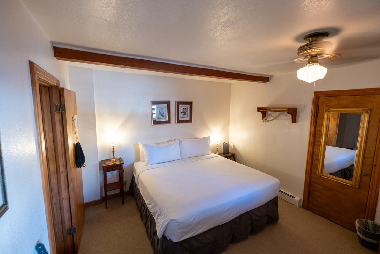 A cozy bedroom featuring a queen-sized bed, wooden furnishings, and soft lighting.