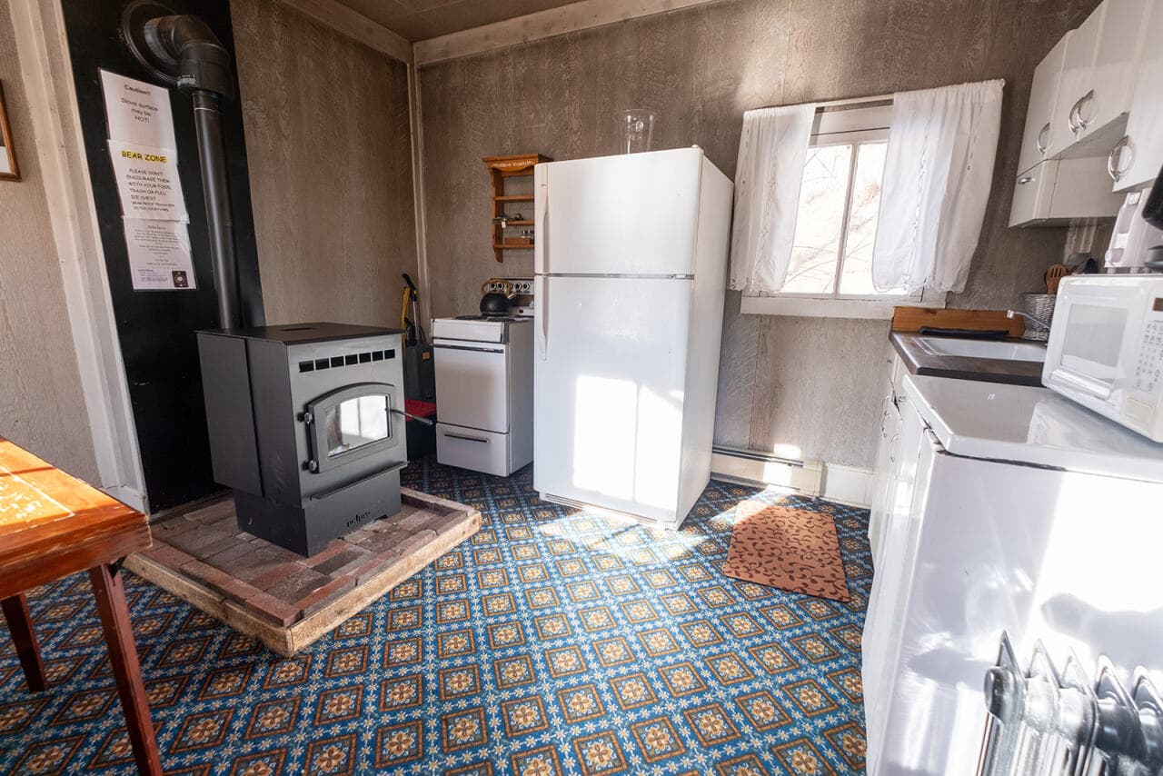 A cozy kitchen featuring a black stove, white appliances, and a patterned blue carpet.