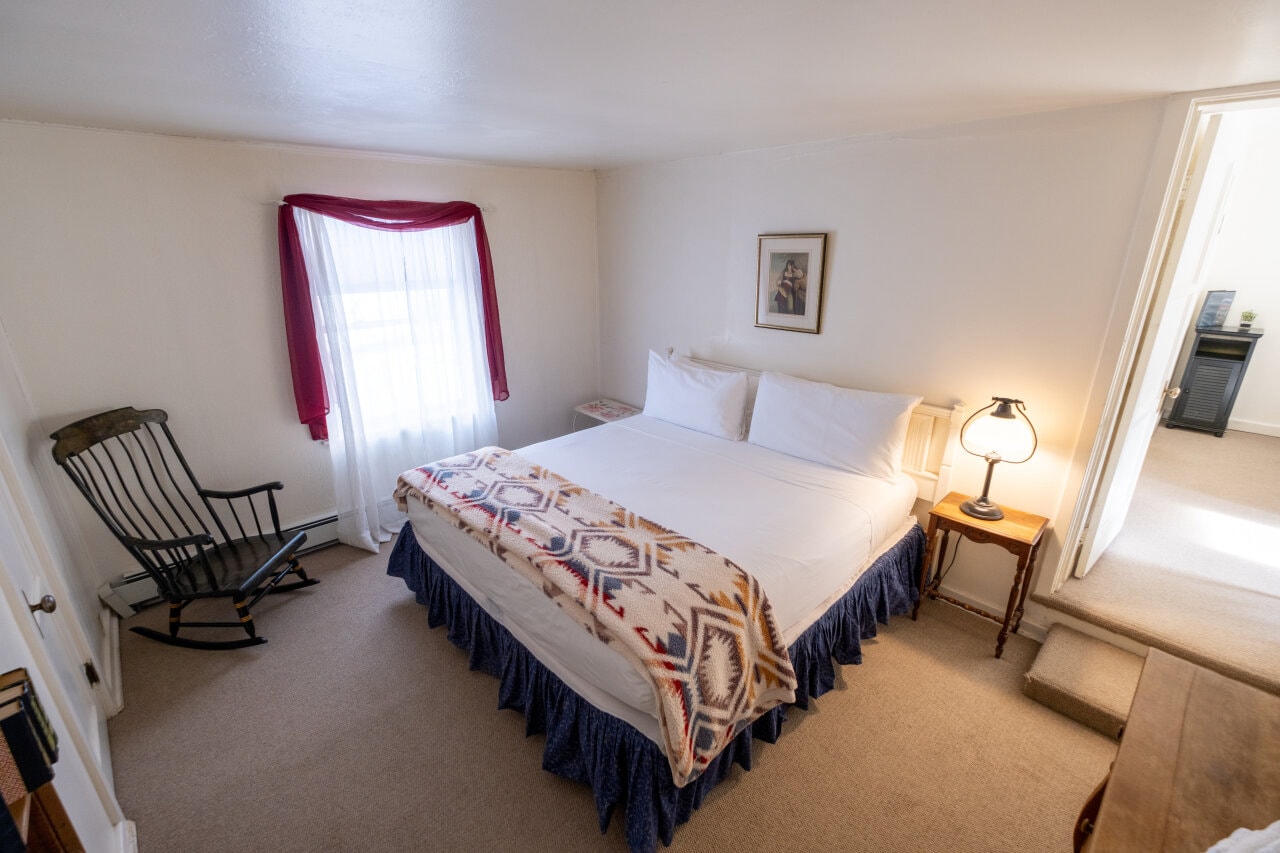 Cozy bedroom with a double bed, rocking chair, and natural light from a window.