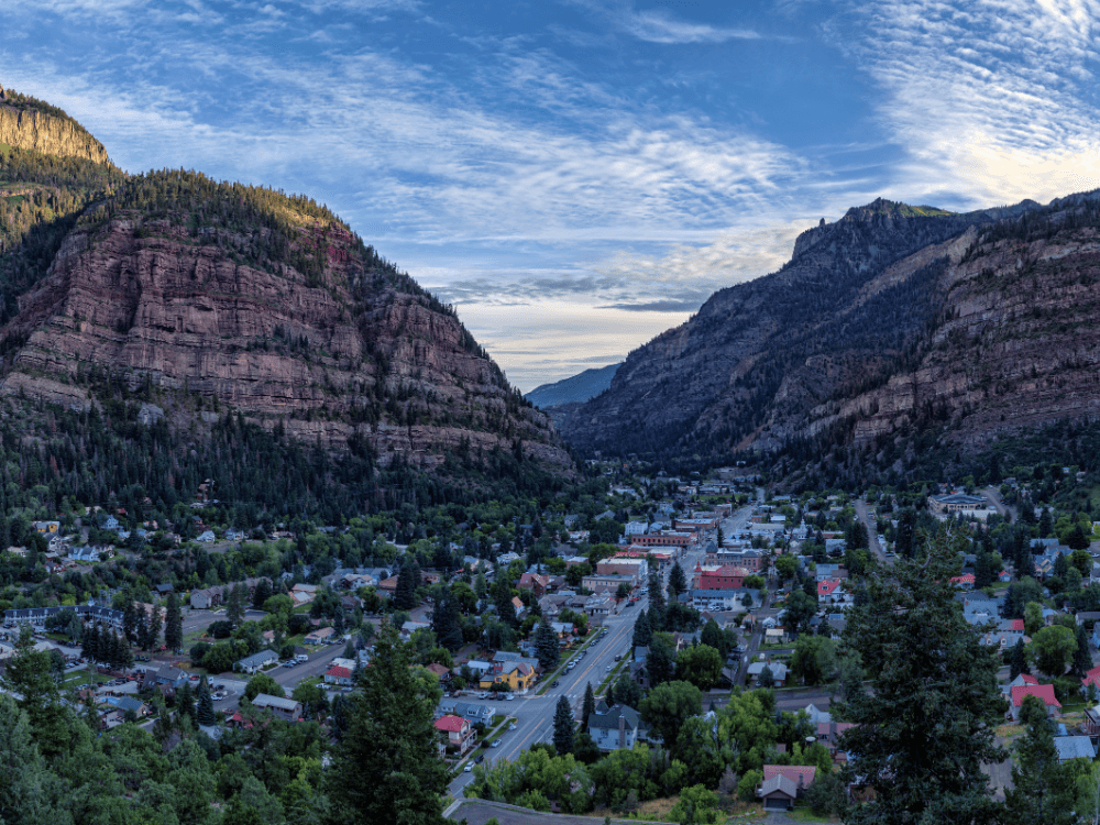 A panoramic view of a valley town surrounded by towering mountains.