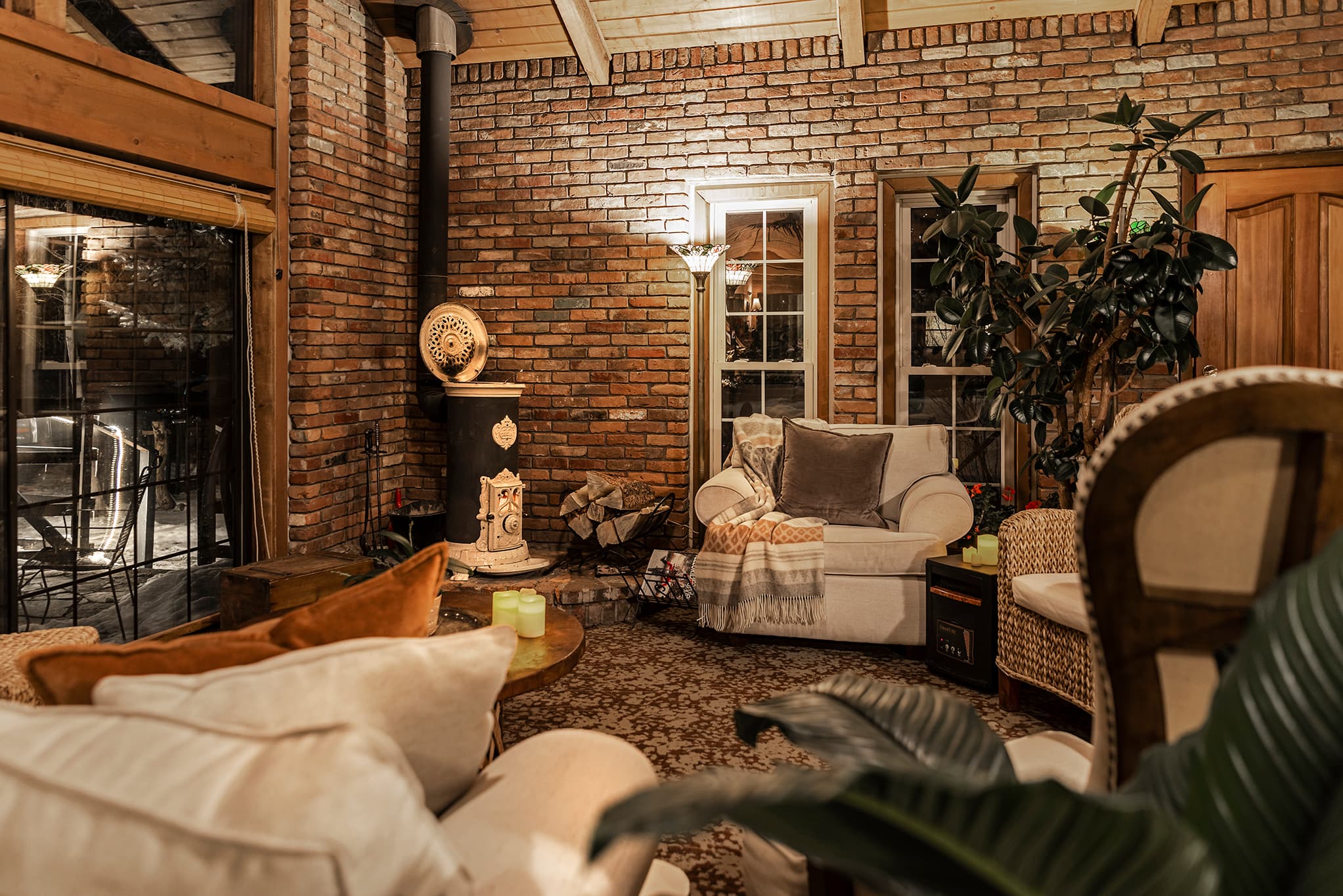Cozy living space featuring a brick wall, comfortable seating, and a wood stove.