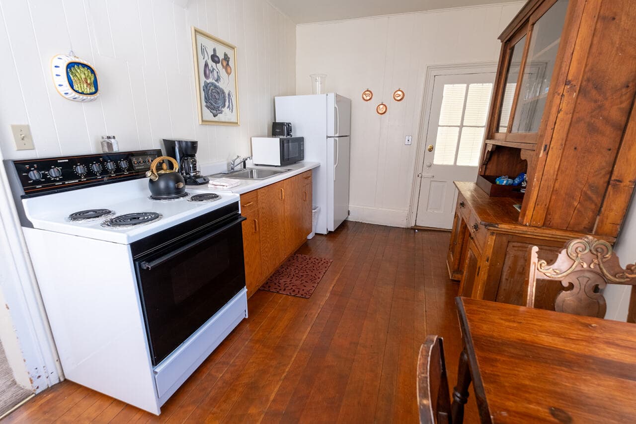A simple kitchen featuring a stove, refrigerator, and wooden dining table.